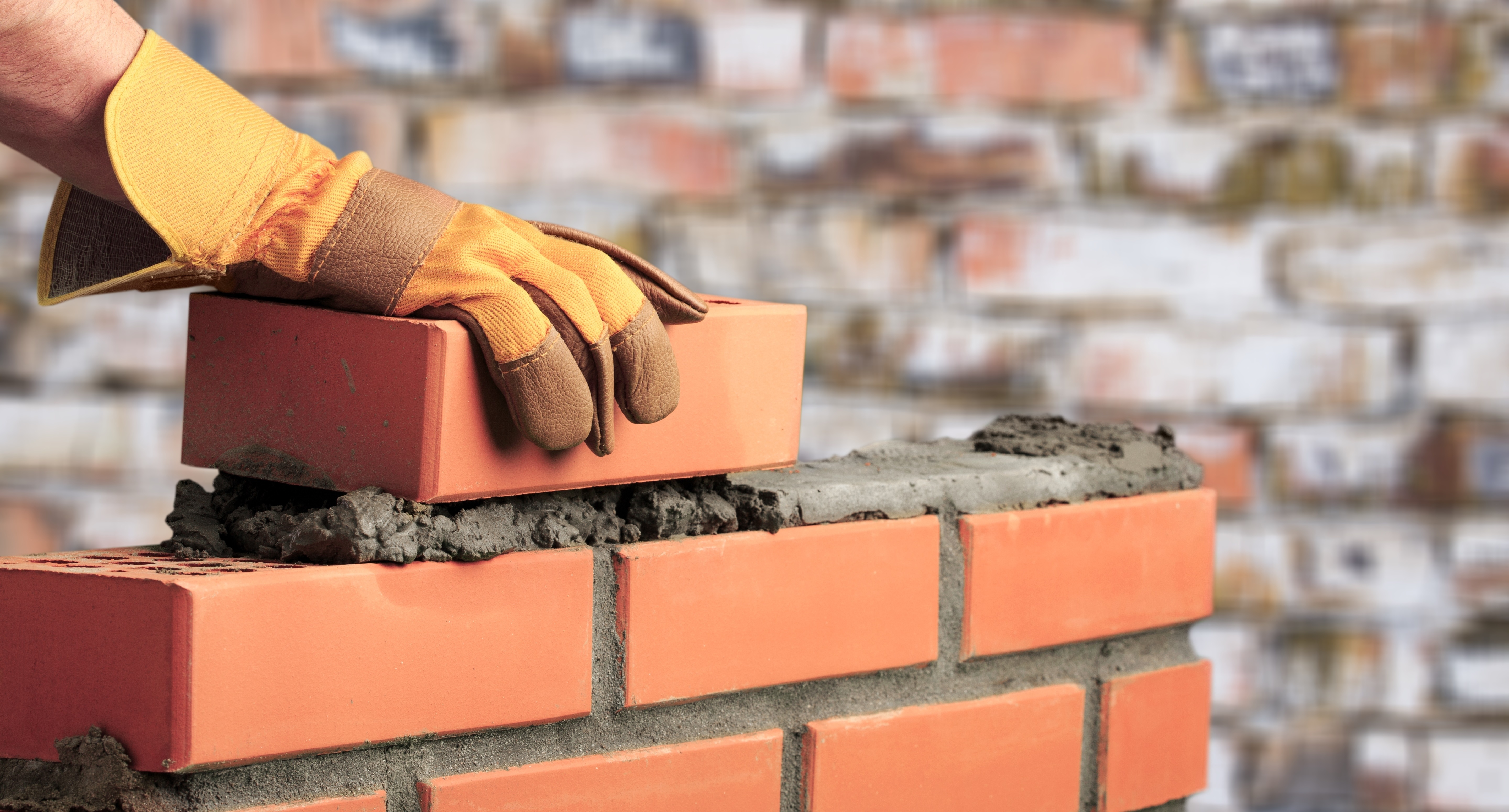 A brick mason preparing a brick in cement.